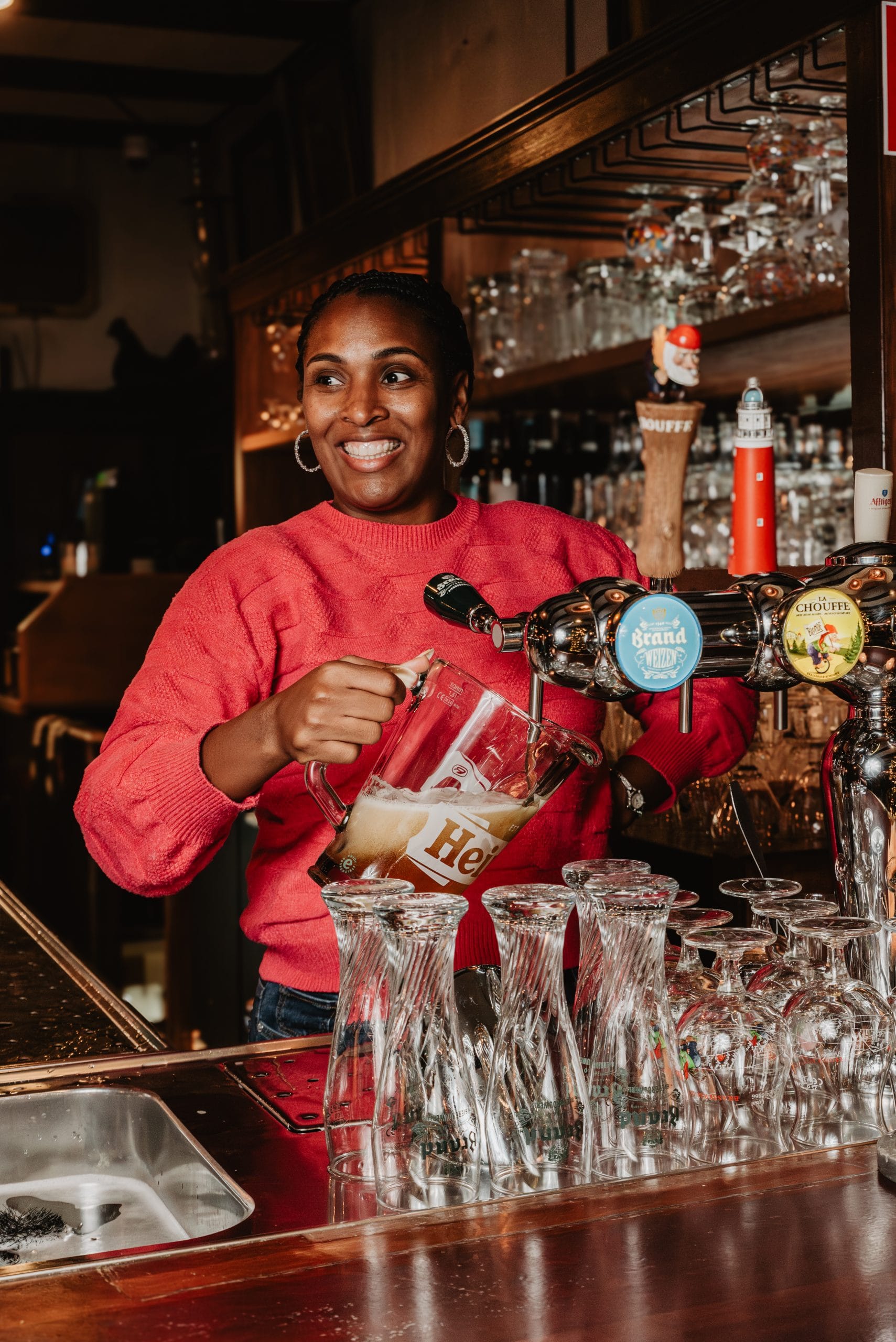 Eigenaresse Maya lacht terwijl ze achter de bar een pitcher tapt
