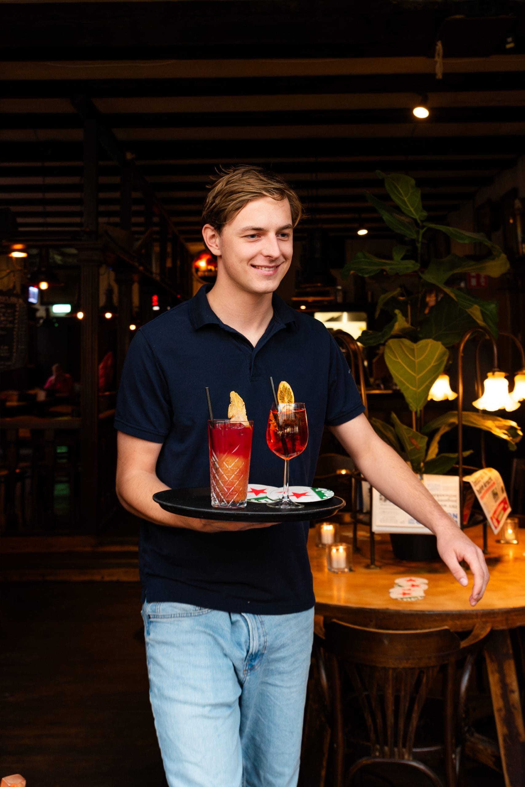 Een medewerker serveert twee cocktails op een dienblad